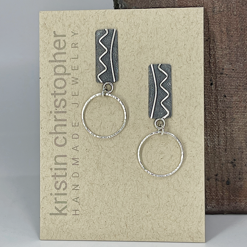 Sterling silver earrings with silver hoops on a 'Kristin Christopher Handmade Jewelry' card.