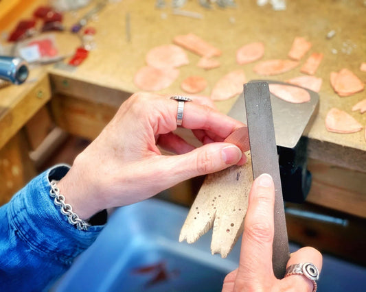 Kristin using a jewelry file to smooth the edge of a copper earring